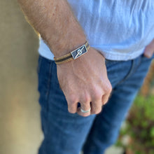 Load image into Gallery viewer, Man with hand in his jeans pocket wearing a Stoke Saver Onewheel™ bracelet in rustic cork with brown inlay strap and stainless steel clasp