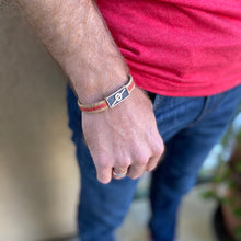Load image into Gallery viewer, Man with hand in his jeans pocket wearing a Stoke Saver Onewheel™ bracelet in rustic cork with red inlay strap and stainless steel clasp
